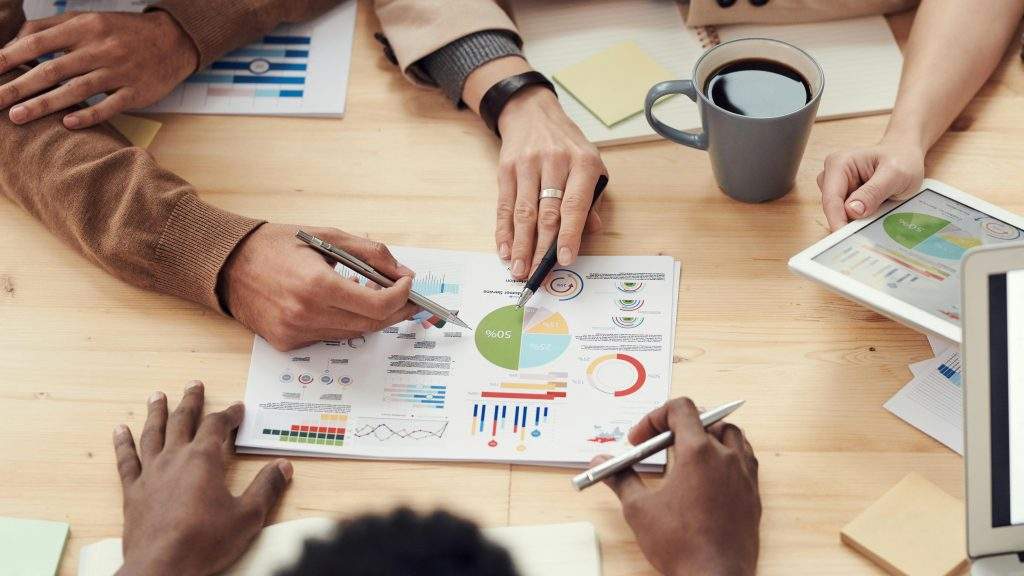 Équipe en réunion collaborant autour de graphiques, symbole de leadership humain et d'intelligence collective