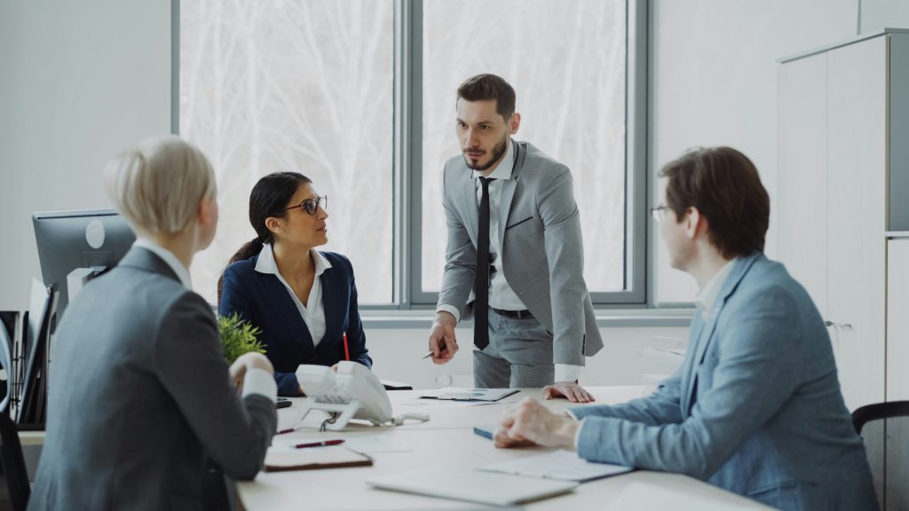 Quatre professionnels échangent autour d’une table de réunion.
