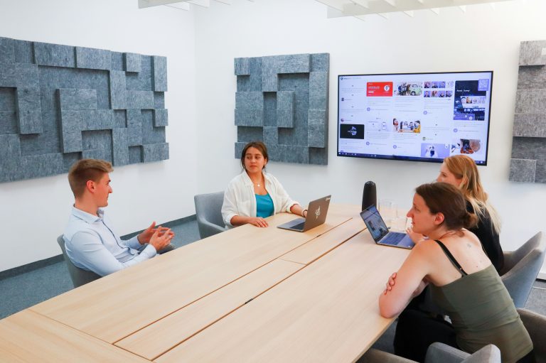 Des collègues réunis autour d’une table face à un écran de présentation.